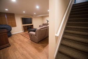 basement staircase leading to finished basement with vinyl plank