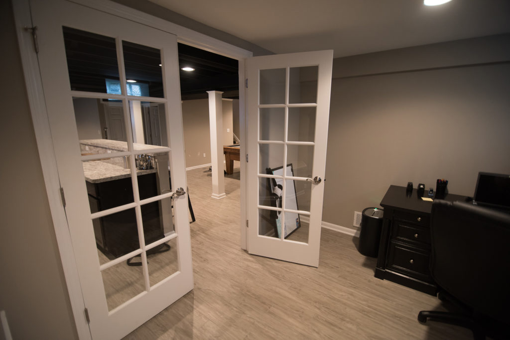home office in basement with french doors and grey vinyl plank flooring