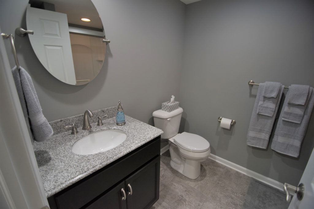 Grey remodeling bathroom with vinyl tile and granite vanity