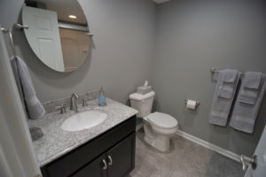 Grey remodeling bathroom with vinyl tile and granite vanity