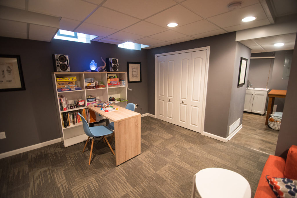 kids area in basement with shelving and table for games