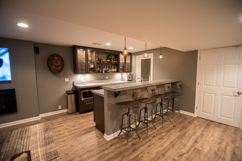 industrial rustic basement bar with concrete countertops and vinyl plank flooring