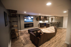 basement living room with rustic furniture and reclaimed looking vinyl plank flooring