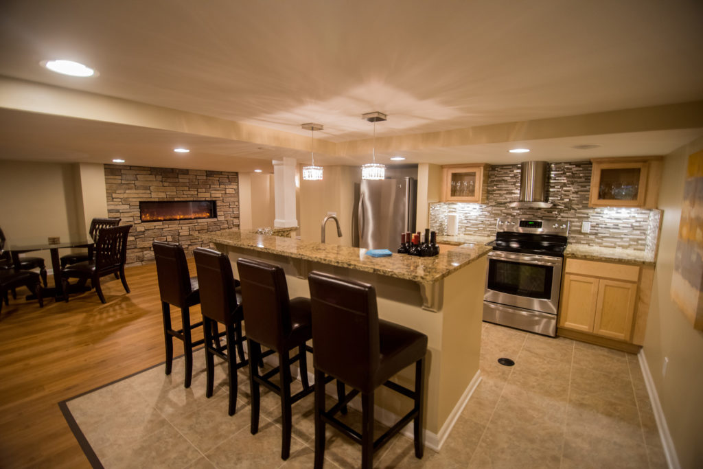 basement kitchen with stone fireplace and glass backsplash