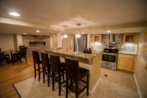 basement kitchen with stone fireplace and glass backsplash