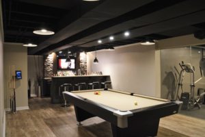 modern basement bar with black painted ceiling and stone bar