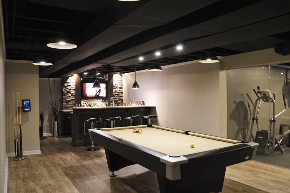 modern basement bar with black painted ceiling and stone bar