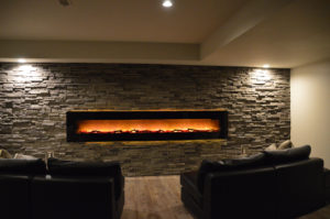 large electric fireplace mounted on the basement wall with rock accent wall