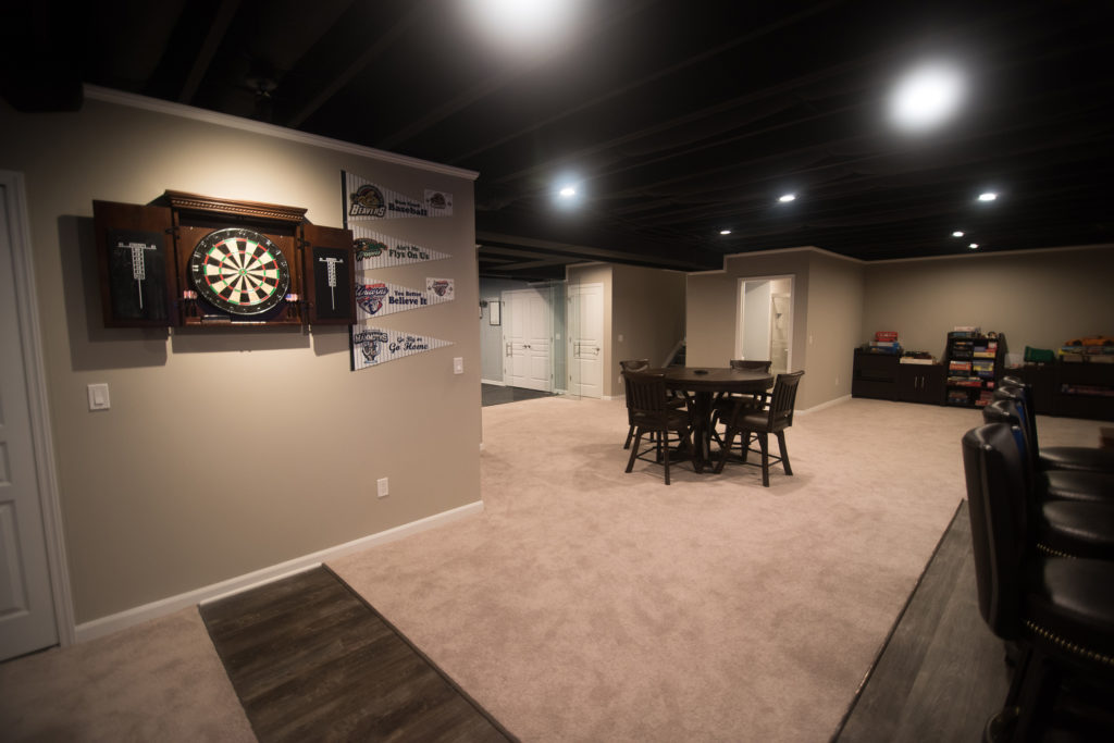 painted black ceilings in a modern Oakland Township, MI basement with a dart board and carpeting