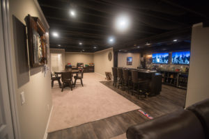 painted ceiling in basement with carpet and large custom bar