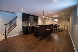 dark vinyl plank flooring in basement with traditional style bar