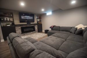 large sofa and tv wall with fireplace and stone in this Wixom, MI basement