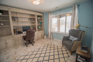 basement office with built in desk and large window