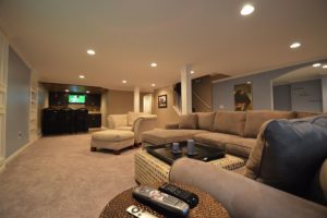 large open basement living room with brown and blue walls a living room sofa and a bar in the end