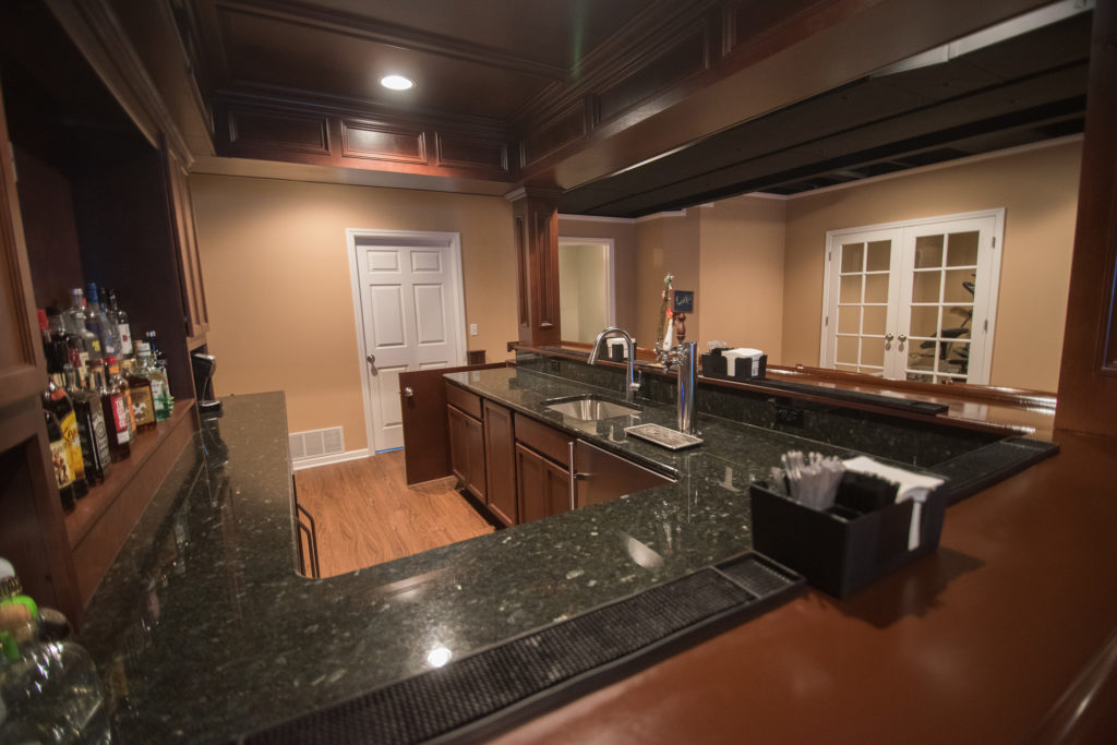 basement bar with granite countertops and vinyl plank flooring