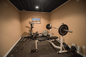basement fitness room with painted ceiling and rubber flooring