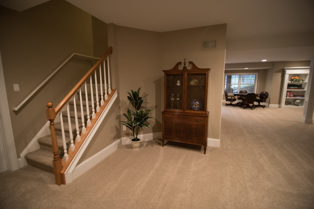 Basement staircase with carpet and wood railing in Washington, Michigan