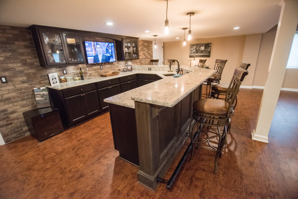 basement bar with dark cabinetry and granite countertops