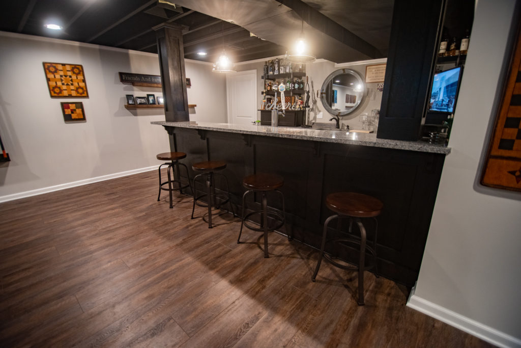 basement bar with dark cabinets and granite countertops