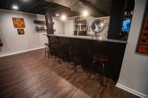 basement bar with dark cabinets and granite countertops