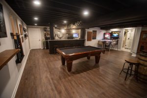 pool table in basement with dark brown vinyl plank flooring and painted ceiling