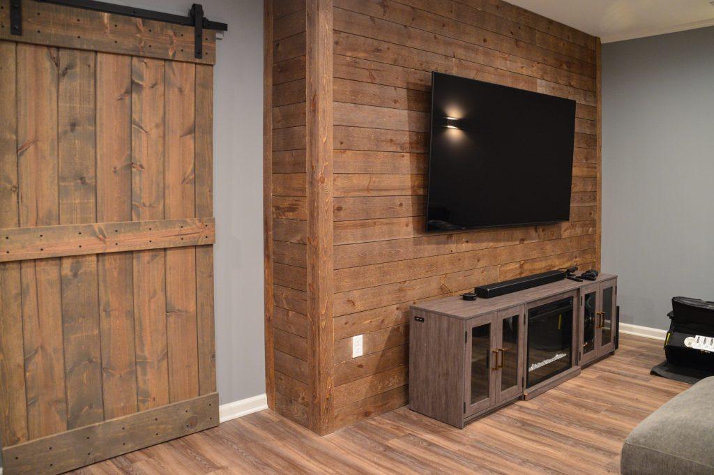 Finished basement living room with shiplap tv wall and sliding wood door in Berkley, Michigan