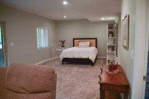 Finished basement view of the guest bed in open area looking from the living room.