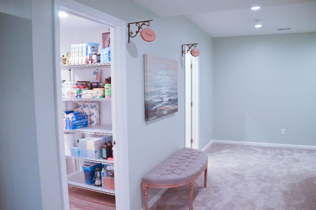 Finished basement hallway looking towards the bathroom and storage doors with custom designed signs displaying what each door leads to.