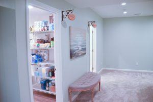 Finished basement hallway looking towards the bathroom and storage doors with custom designed signs displaying what each door leads to.