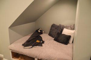Finished basement reading nook built underneath the stairs with blankets and pillows for comfort reading.