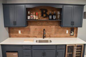 Finished basement wet bar with blue cabinets and wood shiplap backsplash in Berkley, Michigan