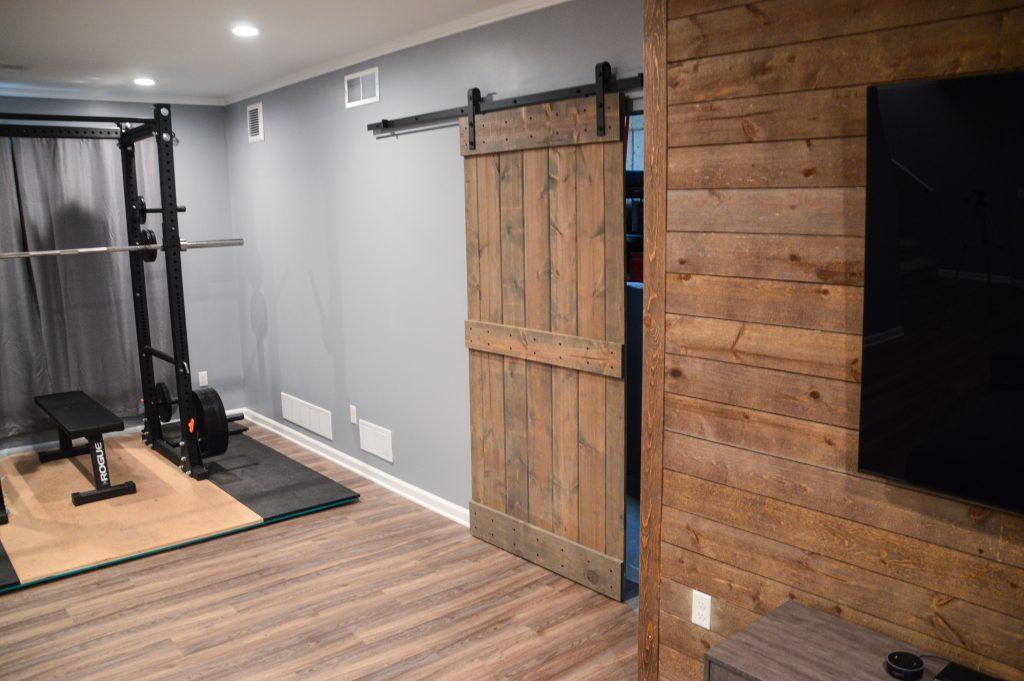 Finished basement living room with shiplap tv wall and sliding wood door in Berkley, Michigan