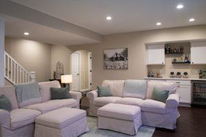 Finished basement living room area with dry bar in the background with spirits and snacks for watching movies.