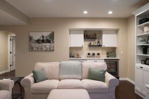 Finished basement living room area with dry bar in the background with spirits and snacks for watching movies.