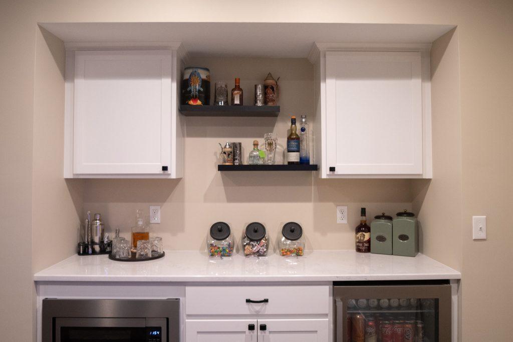 Finished basement snack bar with spirits, snacks and refrigerators to keep beverages cold.