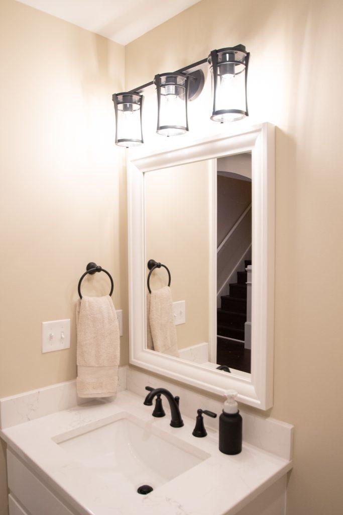 Finished basement bathroom vanity with black faucet, white countertop.
