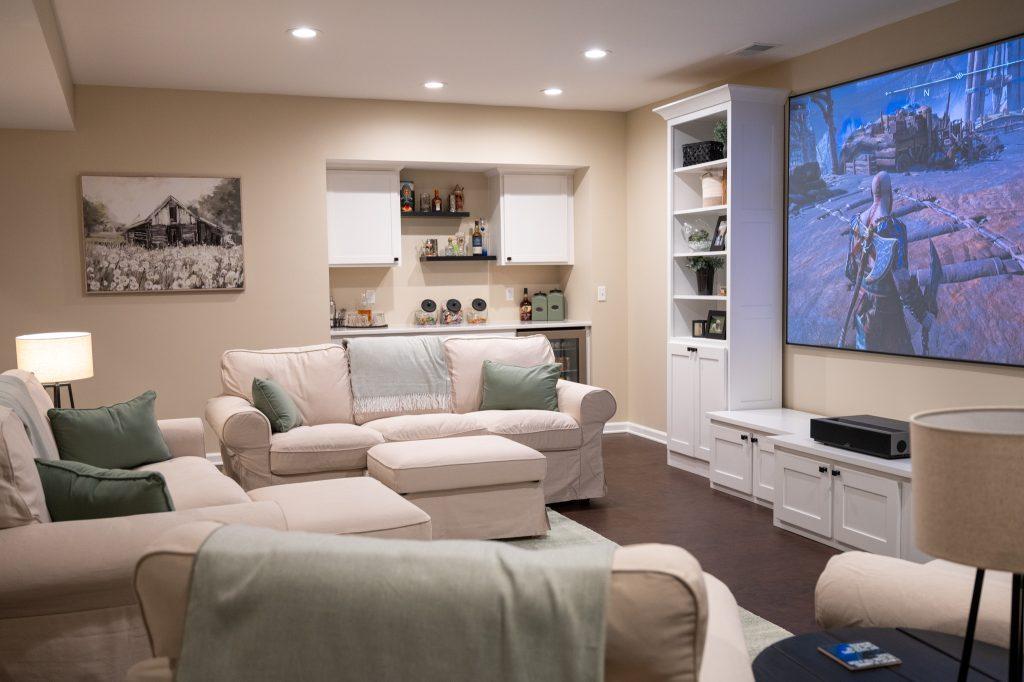 Finished basement living room area with dry bar in the background with spirits and snacks for watching movies.