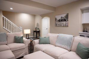 Finished basement living room with the stairs in the background.