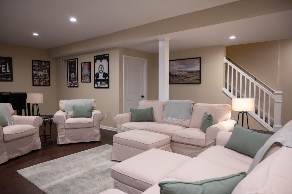 Finished basement living room with the stairs and storage access in the background.