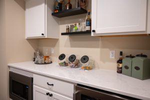 Finished basement snack bar with spirits, snacks and refrigerators to keep beverages cold.