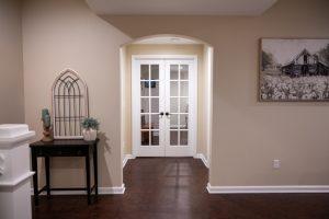 Finished basement looking down the hallway into a double door entrance to the guest room.