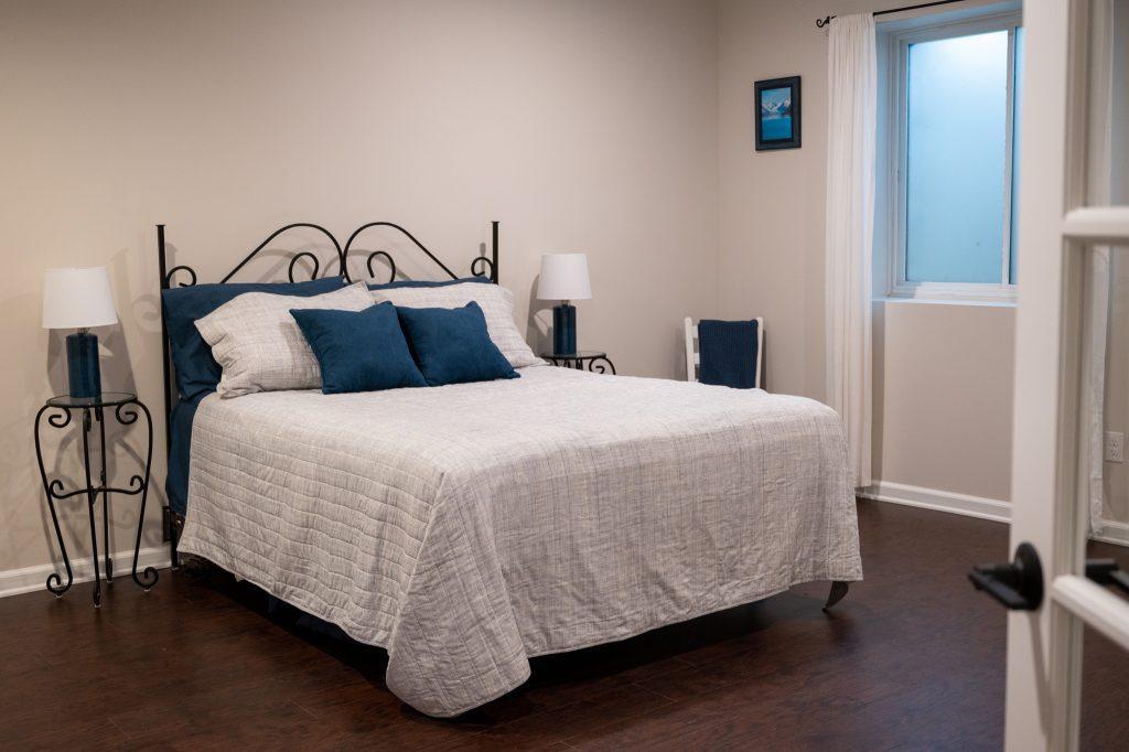 Finished basement guest room with large bed and egress window.