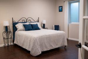 Finished basement guest room with large bed and egress window.