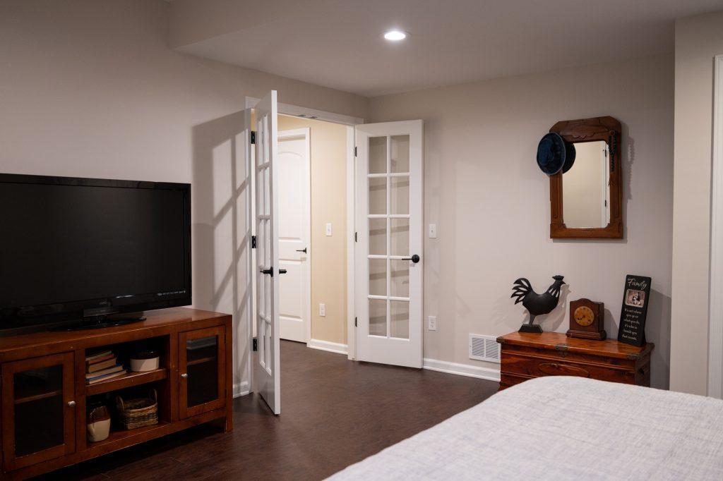 Finished basement guest room look from corner of the room overlooking the bed to the double doors.