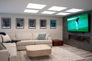 Finished basement living room with coffered ceiling and tile accent wall in Northville, Michigan