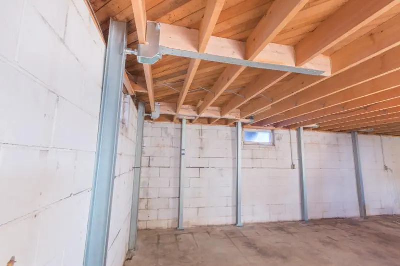 Photo of PowerBrace foundation support beams re-enforcing basement cinderblock walls. Installation by Basements Plus.