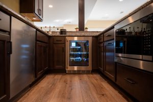 Mini cooler in finished basement with brown cabinets and hardwood flooring